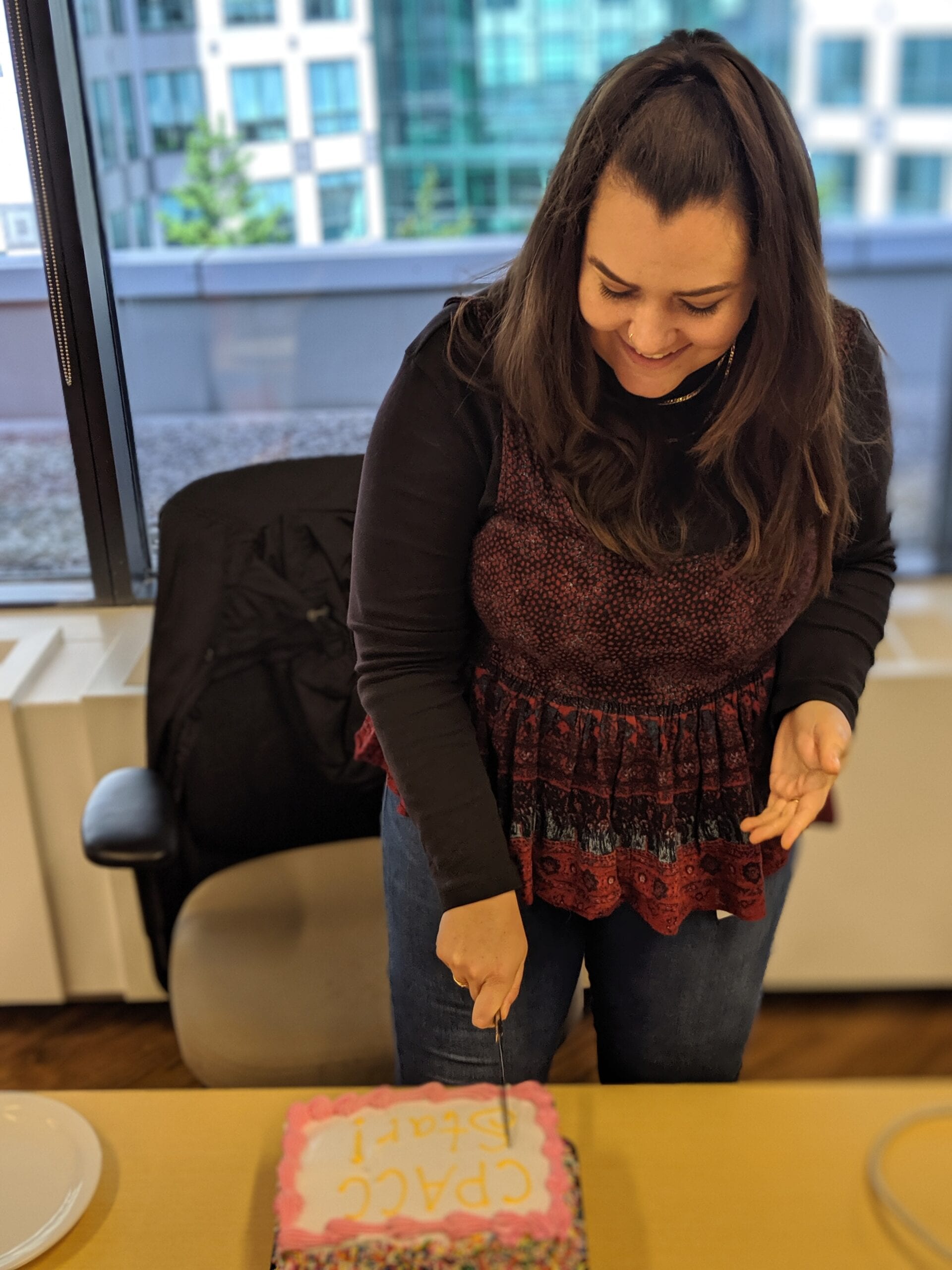 Amber cuts a cake celebrating her CPACC at Fable's office at OneEleven